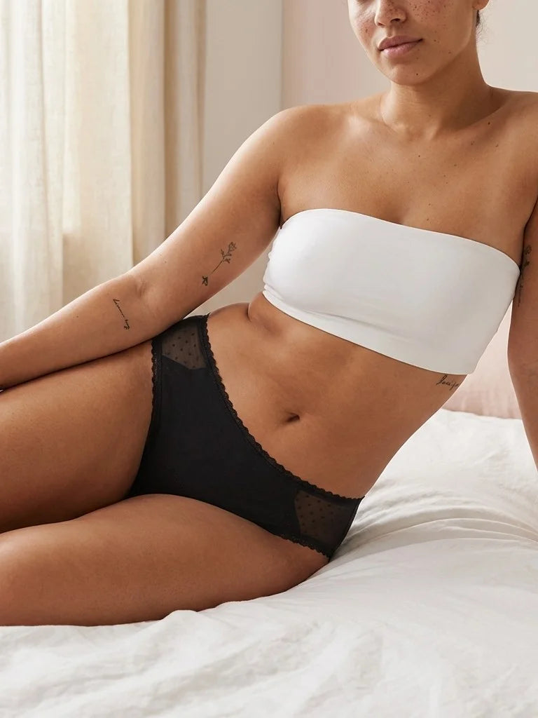 Menstruatie ondergoed zwart, gedragen everyday brief in een ruimer lifestylebeeld op bed